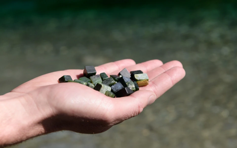 Outstretched hand holding several pounamu (greenstone) pieces
