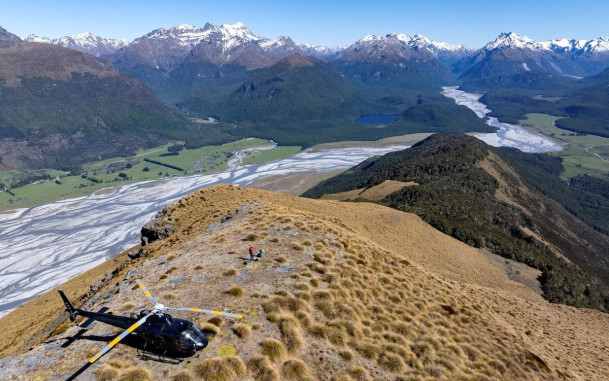 Helicopter on a hill with mountains and Dart River in the background