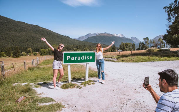 Two people having their photo taken next to the Paradise sign