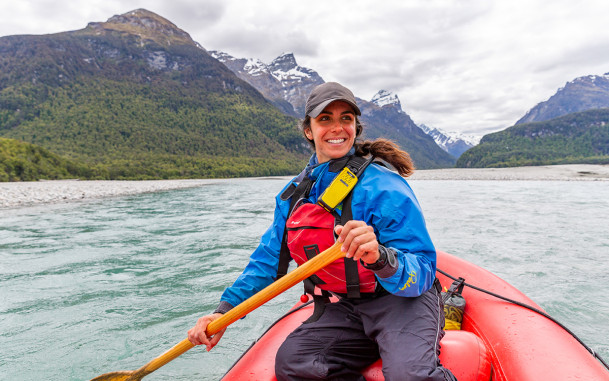 Funyak tour guide in inflatable kayak surrounded by mountains and native forest in Mount Aspiring National Park.