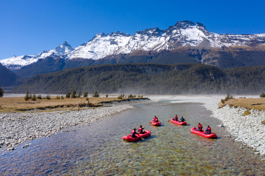 Group paddling Funyaks on the Dart River surrounded by mountains.