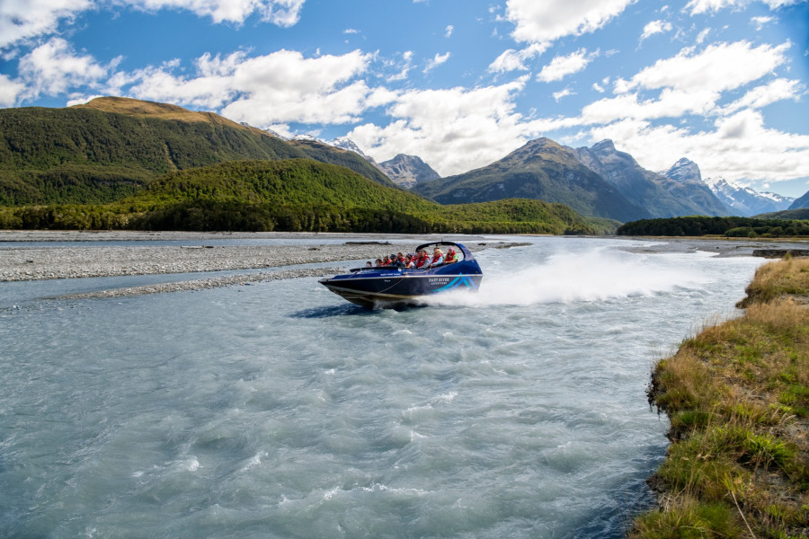 Jet boat speeding along the Dart River with water spraying behind.