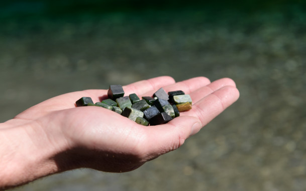Outstretched hand holding several pounamu (greenstone) pieces