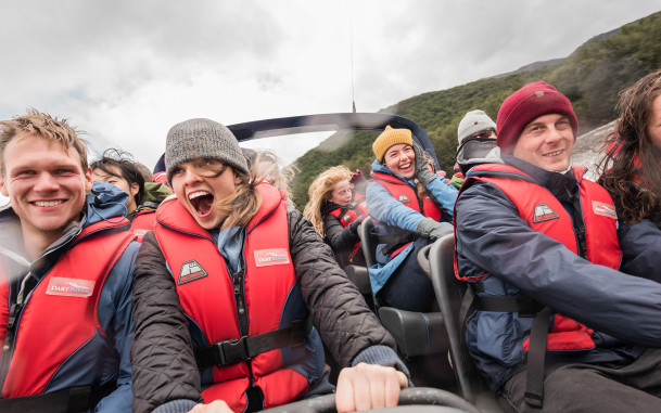 Close-up of visitors on a jet boat as it speeds down the river, with excited, smiling faces.
