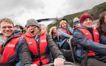 Close-up of visitors on a jet boat as it speeds down the river, with excited, smiling faces.
