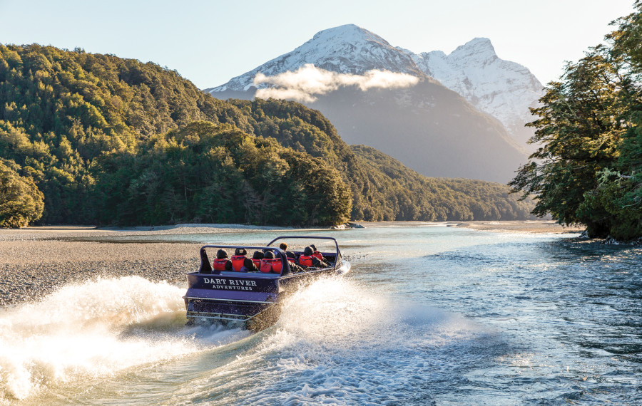 Visitors on board the Wilderness Jet boat on the Dart River, surrounded by native trees and towering mountains