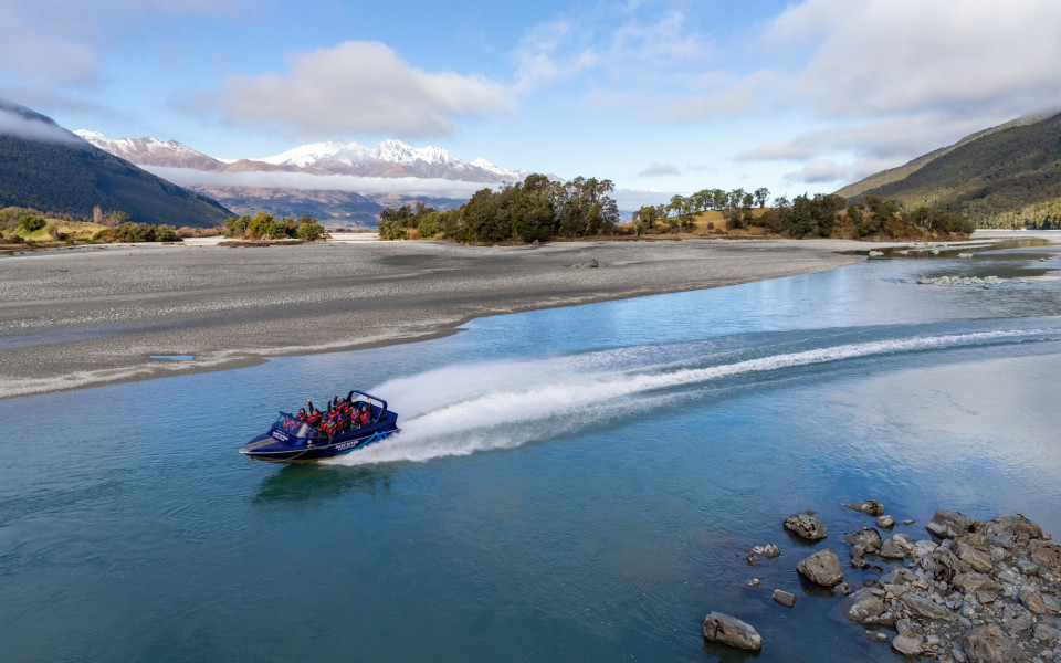 Jet boat speeding along the Dart River with water spraying behind