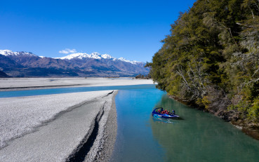 Wilderness Jet boat on the Dart River with passengers onboard and mountains in the background.
